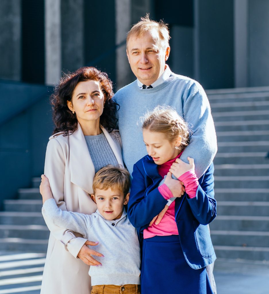 Back to school. happy father, mother, daughter and son go to elementary school. the parents takes the children to primary school. students goes to study with a backpack. the beginning of the lessons. first day of autumn.