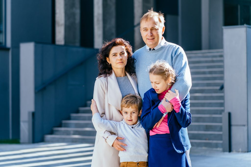 Back to school. happy father, mother, daughter and son go to elementary school. the parents takes the children to primary school. students goes to study with a backpack. the beginning of the lessons. first day of autumn.