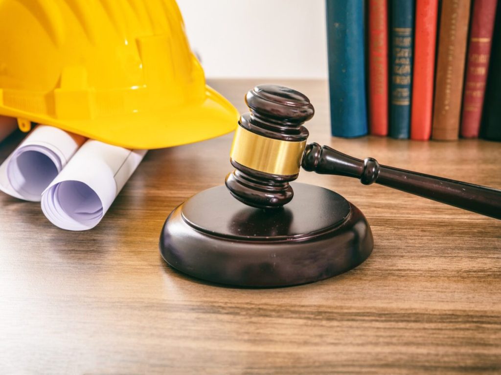 Construction and labor law judge gavel and building drawings on table 1200x900